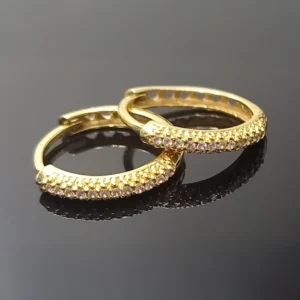 Brinco de diamante feminino em ouro 18k, modelo argola com pedras cravadas e acabamento polido de alto brilho.